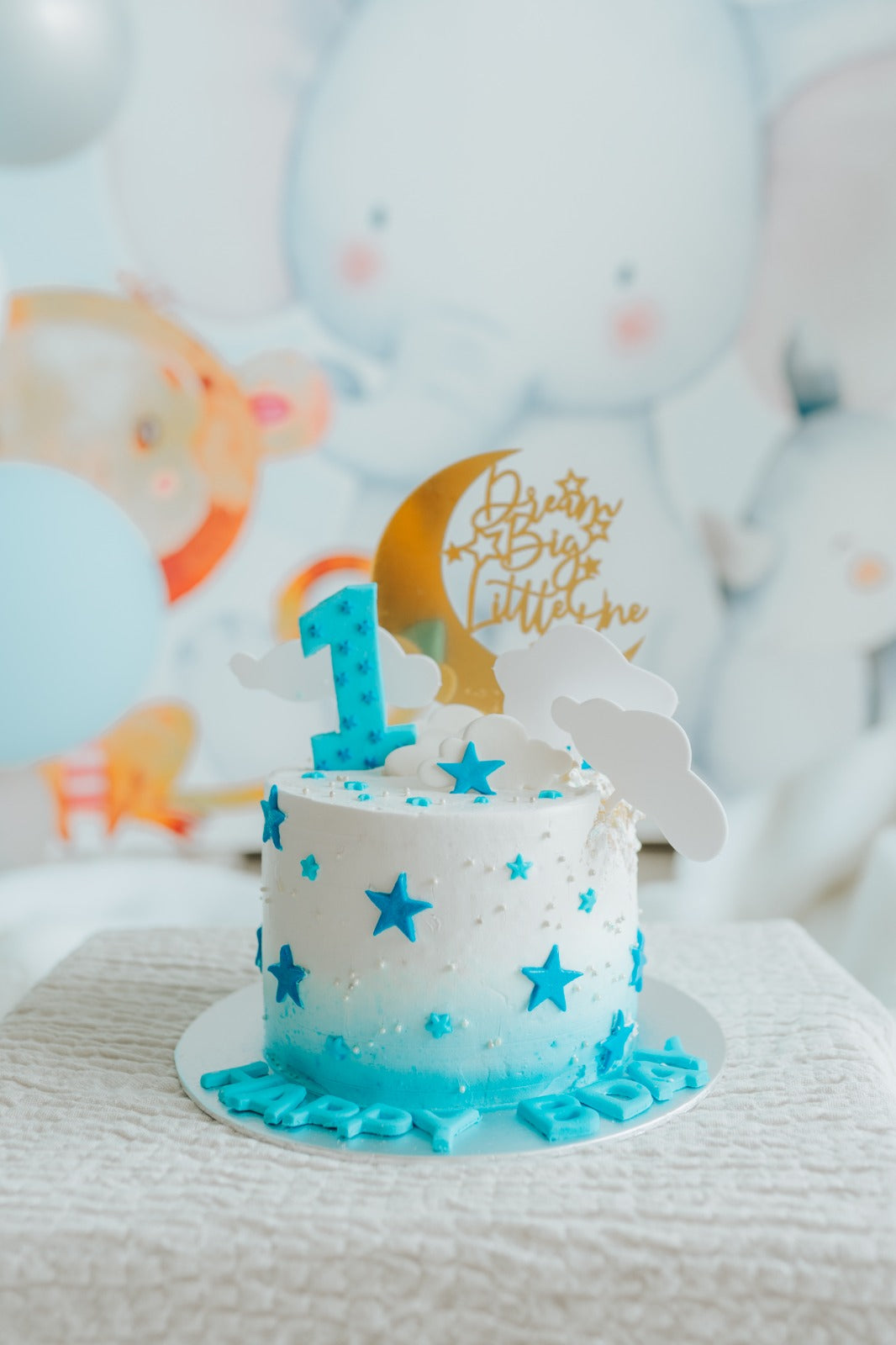 A blue and white cake featuring a prominent number one decoration on top.